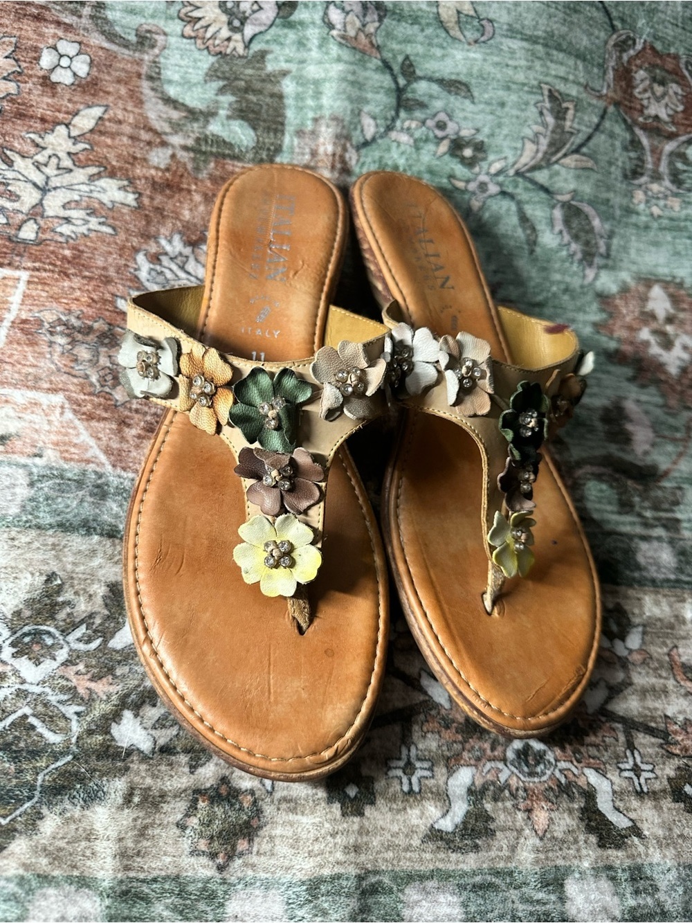 Italian Shoemakers sandals featuring rhinestone-accented floral appliqués.